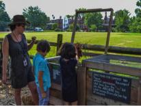 Two children and one adult working looking at compost bins