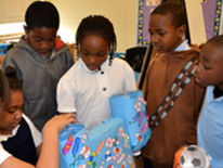 Seaton ES third graders demonstrate their functioning candy dispenser constructed from recyclable water jugs, cardboard boxes, and discarded paper.